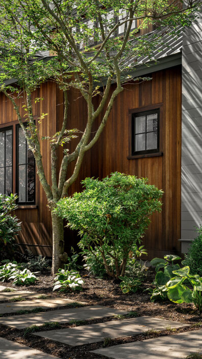Custom outdoor living space with wood siding, modern landscaping, and a stone pathway.